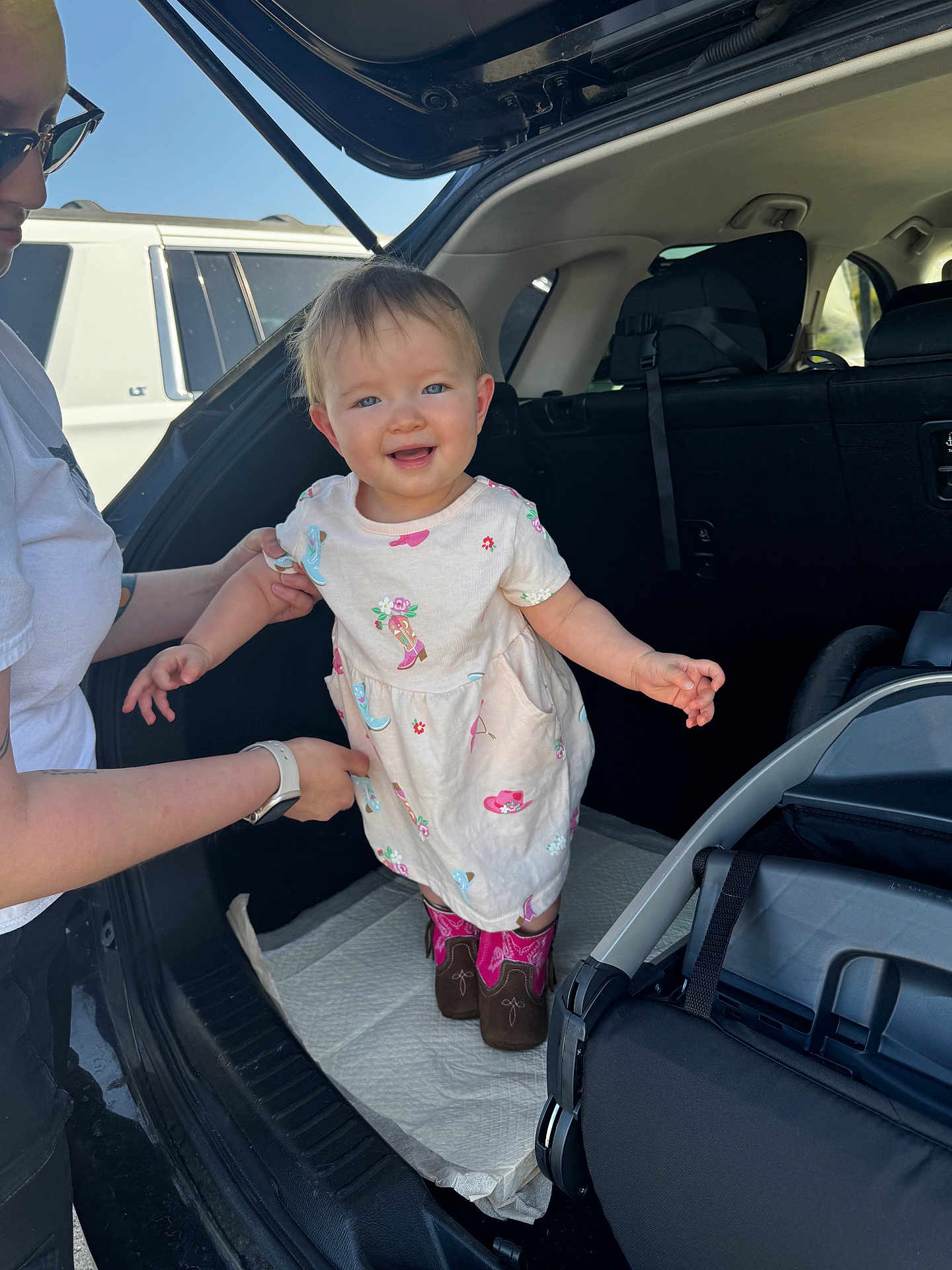 Daniella joined the competition — help win amazing prizes! toddler, child, woman, car, car_trunk, dress, boots, smile, outdoor, daylight, person, vehicle, supporting_hand, baby, casual_clothing, happy, parent, transportation, stroller, sunlight