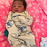 baby, newborn, infant, blanket, pink, floral_pattern, onesie, pacifier, soft_fabric, lying_down, indoors, cute, sleepwear, child, face, head, hand, cozy, comfort, resting