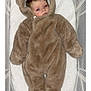 baby, infant, onesie, brown, fuzzy, crib, mesh, cushion, sleepwear, child, face, person, indoors, lying_down, cozy, soft, cute, young, warm, newborn