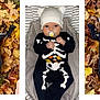 baby, child, infant, skeleton_costume, onesie, hat, pacifier, autumn_leaves, fall, outdoor, indoor, cushioned_seat, cute, holiday, halloween, black_clothing, white_hat, lying_down, sitting, portrait