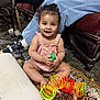 Lara joined the competition — help win amazing prizes! toddler, child, smiling, curly_hair, indoor, carpet, toy, slinky, colorful, sitting, happy, person, footwear, chair, couch, adult, casual_clothing, floor, hand, play