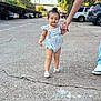 toddler, child, person, walking, hand_holding, romper, sandals, sidewalk, street, cars, trees, daylight, blue_sky, outdoor, concrete, crack, adult, clothing, footwear, support