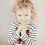 child, freckles, blonde_hair, curly_hair, striped_shirt, sequin, heart_shape, hands_clasped, smiling, portrait, cute, young_child, innocent, light_background, indoor, person, face, happy, playful, toddler