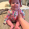baby, bed, bedroom, blanket, child, clothing, cute, face, floral_pattern, foot, hand, hat, indoors, infant, person, quilt, sitting, skin, smile, support