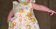 Jennalynn is registered to the contest to win money with this photo: baby, pacifier, head_wrap, dress, lion_print, couch, arm, pink, blue_eyes, infant, indoor, person, child, cute, lying_down, fabric, pattern, soft_toys, comfort, portrait
