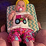 Jennalynn is registered to the contest to win money with this photo: baby, child, pacifier, headband, yellow_bow, shirt, colorful_clothing, patterned_shorts, zigzag_cushion, wood_floor, legs, feet, infant, sitting, indoor, cute, pink, white_shirt, playful, person