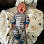 Rowan is registered to the contest to win money with this photo: baby, infant, onesie, striped_clothing, yawning, blanket, star_pattern, couch, soft_texture, sleepy, cozy, indoor, child, portrait, cute, relaxation, newborn, comfort, fabric, resting