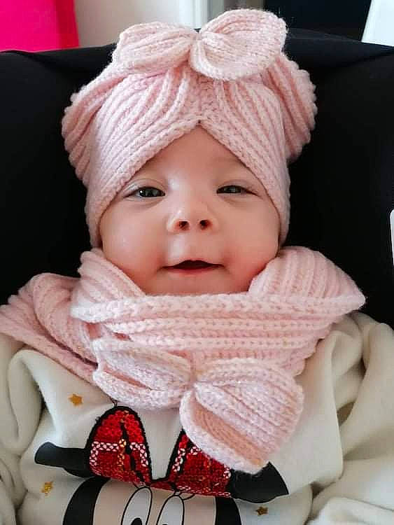 Maëlys participe au concours pour gagner de l'argent avec cette photo : baby, baby_toddler_clothing, cap, cheek, comfort, eye, eyebrow, face, happy, head, headwear, knit_cap, lip, outerwear, person, pink, skin, sleeve, smile, textile
