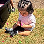 toddler, child, grass, outdoor, water_balloons, toy, pink_bow, black_crocs, socks, sunlight, summer, playtime, balloon_fragments, casual_clothing, person, daylight, closeup, cute, curly_hair, nature