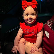 Briar joined the competition — help win amazing prizes! baby, child, red_bow, red_clothing, smile, indoor, car_interior, night, adult_hand, holding, cute, portrait, chubby_cheeks, headband, person, happy, eyes, face, infant, sitting