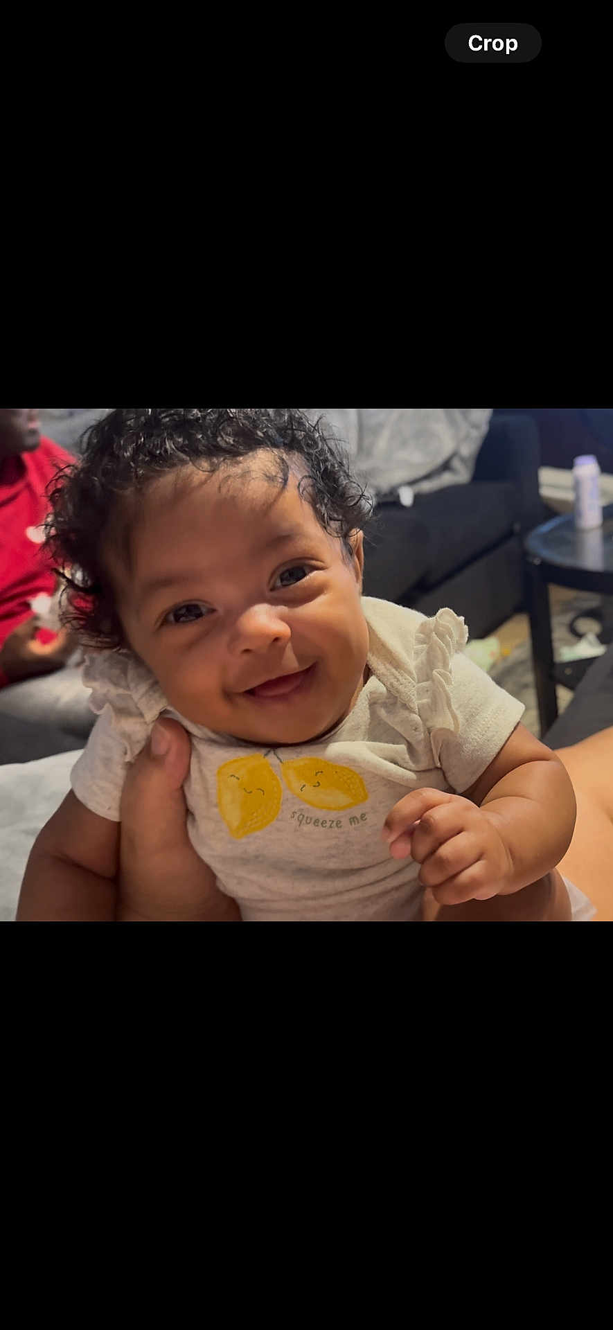 Lyric joined the competition — help win amazing prizes! baby, child, smiling, curly_hair, shirt, lemon, hand, person, indoor, couch, table, living_room, happy, cute, infant, portrait, clothing, human, face, sitting