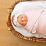 newborn, baby, sleeping, swaddled, pink, headband, basket, woven, wooden_floor, infant, peaceful, cozy, cute, portrait, child, resting, soft, indoors, blanket, adorable