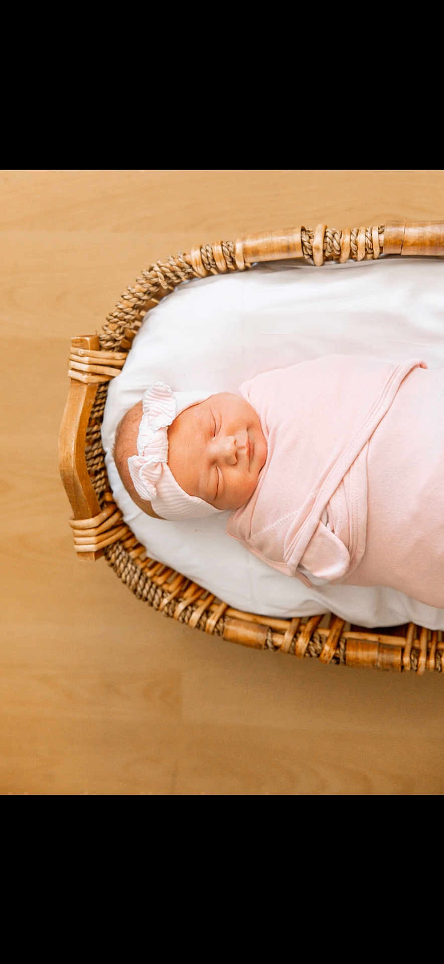 Lennon is registered to the contest to win money with this photo: newborn, baby, sleeping, swaddled, pink, headband, basket, woven, wooden_floor, infant, peaceful, cozy, cute, portrait, child, resting, soft, indoors, blanket, adorable