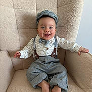Gabriel a rejoint le concours — aidez-le/la à gagner de superbes lots ! baby, child, smiling, face, hat, bow_tie, suspenders, shirt, pants, barefoot, armchair, furniture, indoors, happy, cute, portrait, seated, cozy, clothing, person
