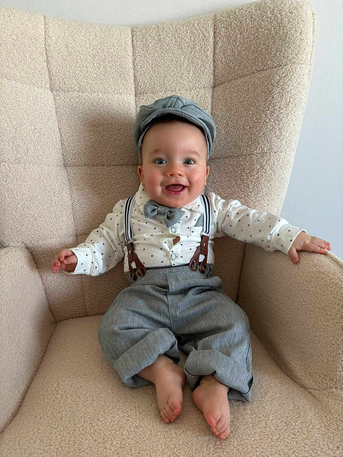 Gabriel a rejoint le concours — aidez-le/la à gagner de superbes lots ! baby, child, smiling, face, hat, bow_tie, suspenders, shirt, pants, barefoot, armchair, furniture, indoors, happy, cute, portrait, seated, cozy, clothing, person