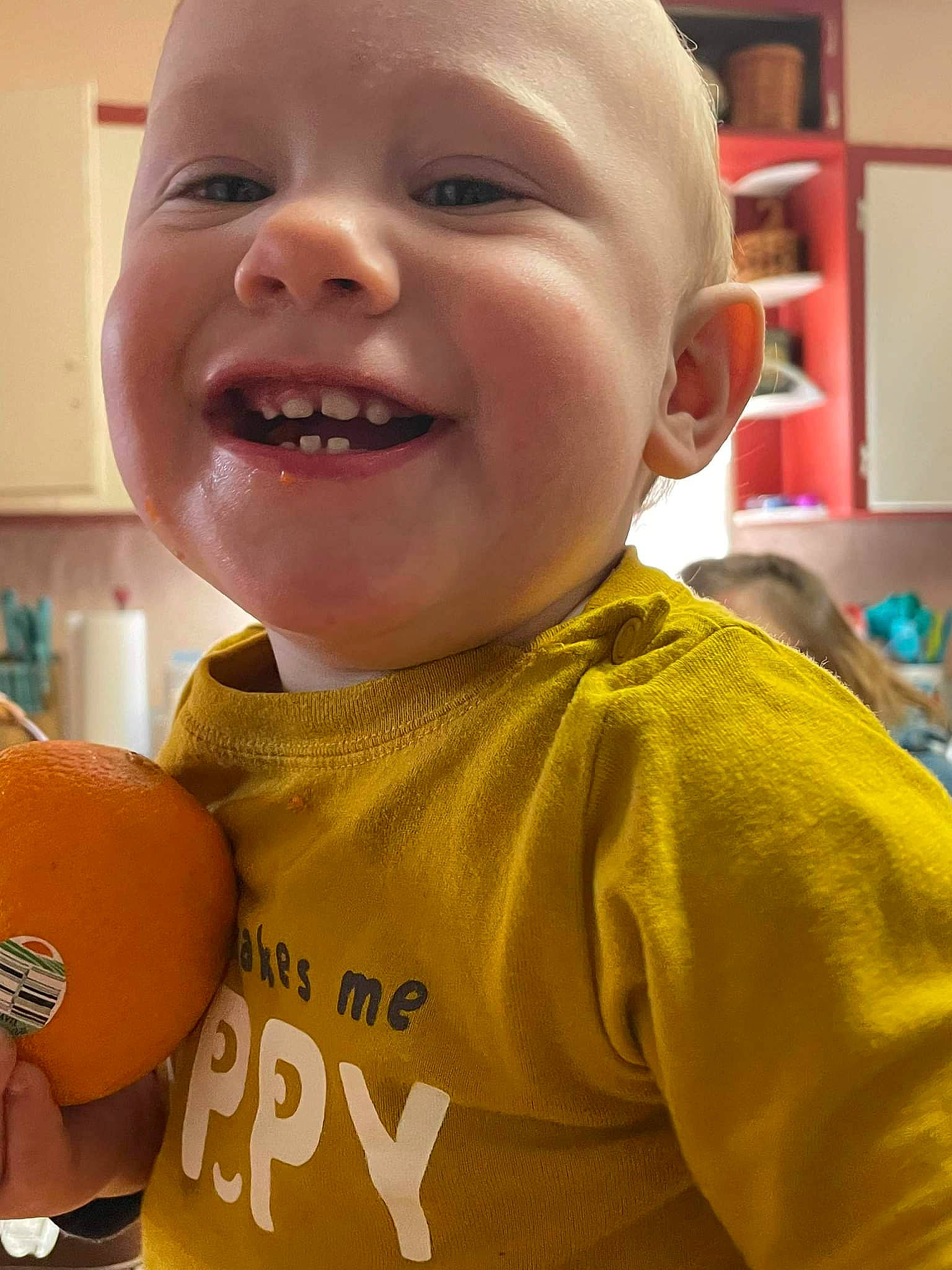 Cannon is registered to the contest to win money with this photo: cheek, chin, eye, eyebrow, facial_expression, finger, forehead, gesture, happy, head, human_body, iris, joy, mouth, neck, nose, orange, person, shelf, skin