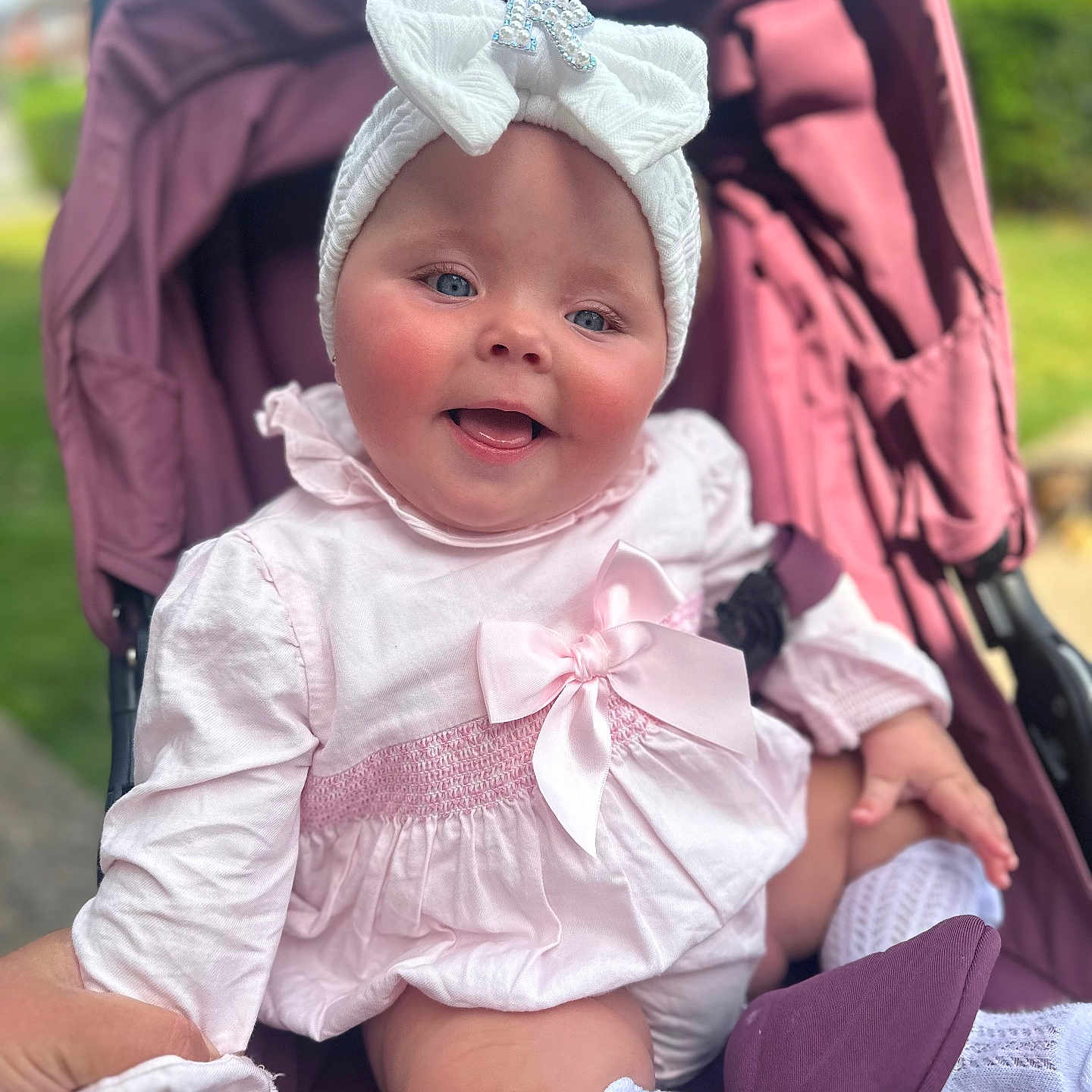 Rylah-Mae joined the competition — help win amazing prizes! baby, baby_clothes, bow, child, clothing, cute, face, hand, happy, headband, infant, nature_background, outdoor, person, pink_dress, portrait, seat, smiling, sock, stroller