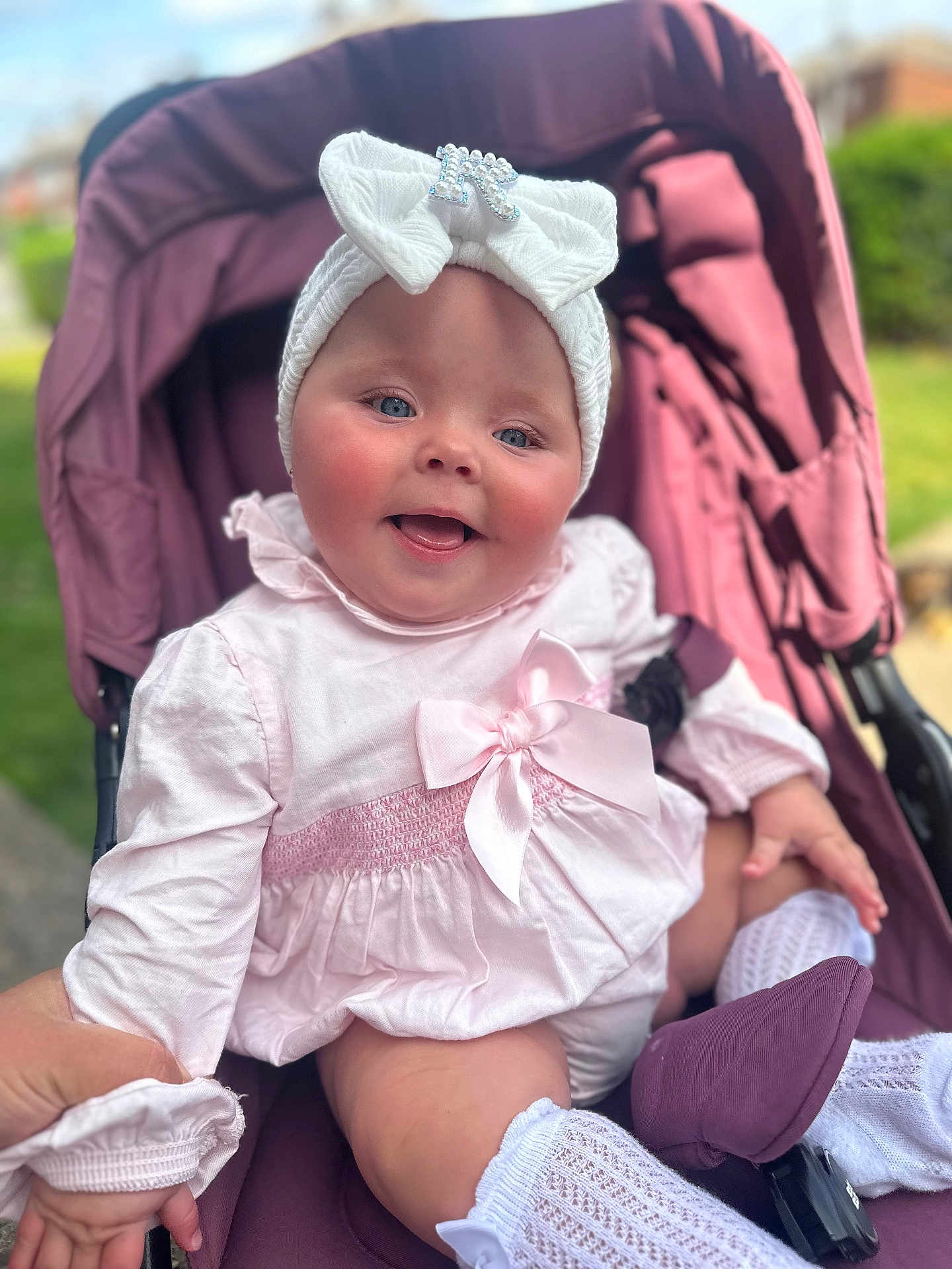 Rylah-Mae joined the competition — help win amazing prizes! baby, baby_clothes, bow, child, clothing, cute, face, hand, happy, headband, infant, nature_background, outdoor, person, pink_dress, portrait, seat, smiling, sock, stroller