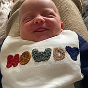 Myles joined the competition — help win amazing prizes! baby, smiling, bib, clothing, infant, face, closed_eyes, cozy, blanket, texture, home, person, cute, happy, resting, soft, warm, child, portrait, seated