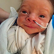 Elias is registered to the contest to win money with this photo: newborn, baby, infant, child, face, eyes, smiling, portrait, close_up, blanket, swaddled, hospital, medical, nasal_tube, tape, bedding, soft_lighting, indoors, head, photography