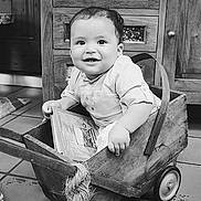 Saned participe au concours pour gagner de l'argent avec cette photo : barefoot, black_and_white, book, cabinet, candid, child, curly_hair, floor_tiles, furniture, home_interior, indoor, person, plush_toy, portrait, rug, shirt, smiling, toddler, wagon, wooden_wagon