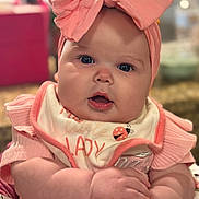 Eliana joined the competition — help win amazing prizes! baby, infant, headband, bow, bib, chubby_cheeks, hands, dress, floral_pattern, pink, portrait, close_up, eyes, mouth, cute, smile, skin, indoor, bokeh, accessory