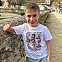 boy, building, castle, casual, child, daylight, happy, nature, outdoor, pathway, person, short_hair, smile, standing, stone_wall, thumbs_up, trees, tshirt, village, white_clothing