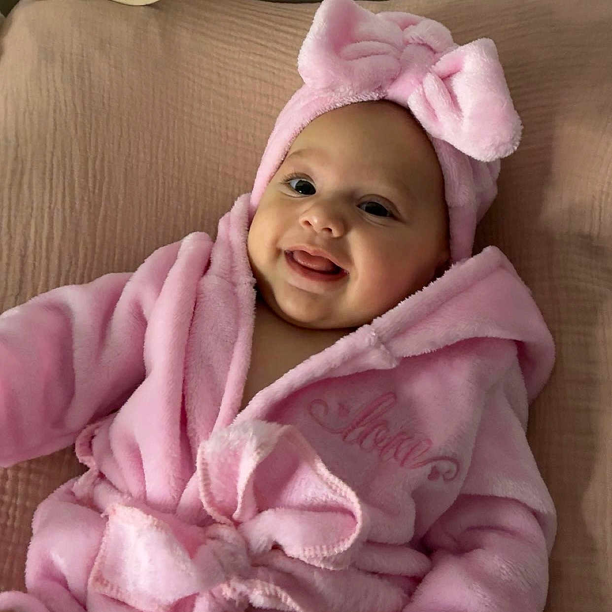 Eve a rejoint le concours — aidez-le/la à gagner de superbes lots ! baby, blanket, bow, child, clothing, cozy, cute, face, happy, headwear, indoors, infant, lying, pink, portrait, robe, smile, soft, toddler, warm