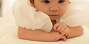 Emma is registered to the contest to win money with this photo: baby, infant, child, portrait, white_bow, bracelet, soft_lighting, cream_cushion, white_dress, closeup, adorable, cute, hands, face, expression, indoor, soft_texture, headband, pensive, newborn