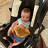 baby, blanket, car_seat, carpet, child, clothing, comfort, cute, fabric, footwear, home, indoor, infant, person, plush, seat, smiling, soft_toy, teddy_bear, toy