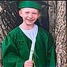 achievement, celebration, ceremony, child, childhood, clothing, diploma, event, graduate, graduation_cap, green_gown, happy, holding, nature, outdoor, person, portrait, smiling, tree, young