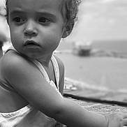 Léïa participe au concours pour gagner de l'argent avec cette photo : toddler, child, black_and_white, portrait, curly_hair, outdoor, sea, sky, clouds, brick, wall, sleeveless_top, person, young_child, face, expression, candid, leaning, daytime, nature