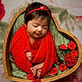 baby, sleeping, red_shawl, heart_shaped_bowl, roses, flowers, headband, peaceful, infant, cute, newborn, soft_texture, wrapped, cozy, portrait, closeup, decorative, warm_colors, flower_arrangement, adorable