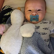 Takoda joined the competition — help win amazing prizes! baby, bed, blanket, child, clothing, comfort, cozy, cute, duck, face, indoor, infant, lying_down, pacifier, portrait, sleepwear, smile, soft_toy, stuffed_animal, toddler