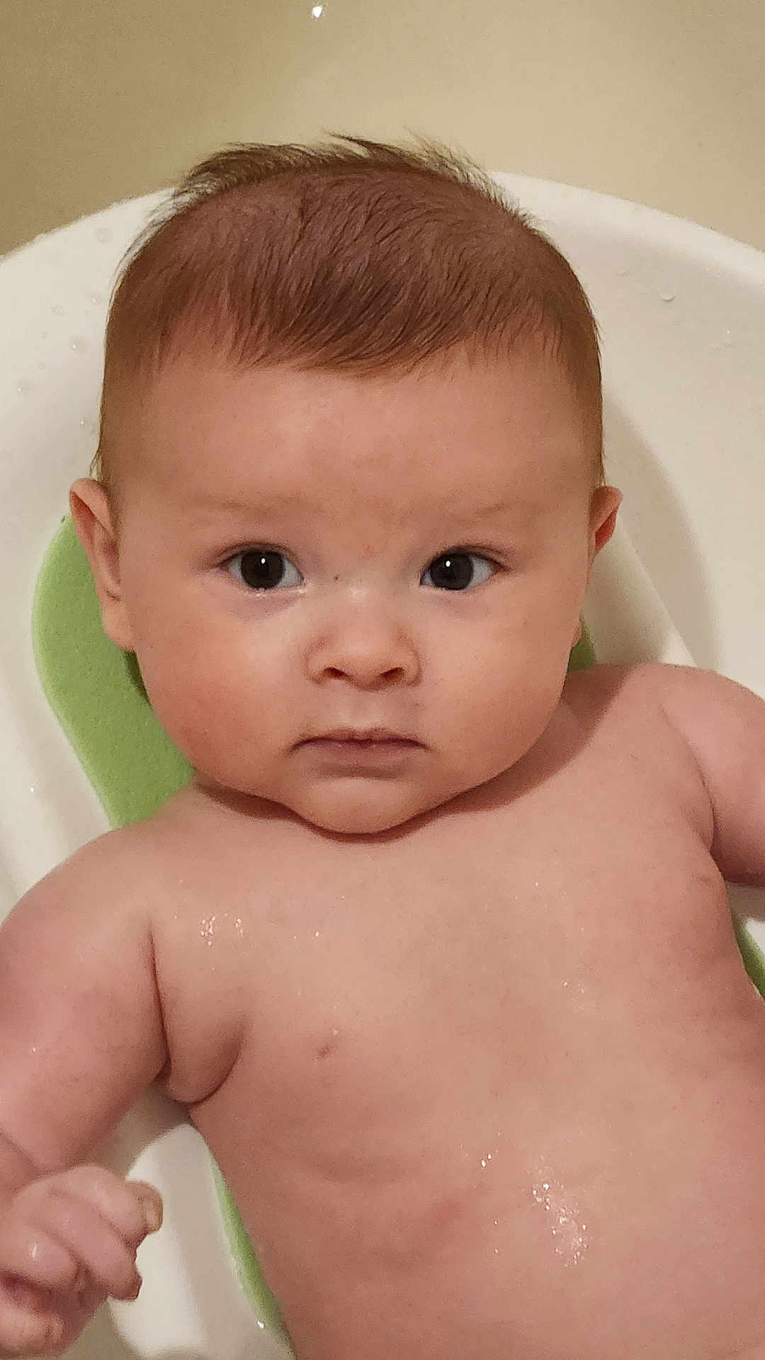 Takoda is registered to the contest to win money with this photo: baby, infant, face, skin, wet, bath, bathtub, child, water, young, expression, looking, curious, naked, seat, head, arms, human, indoors, portrait