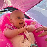 éléonore a rejoint le concours — aidez-le/la à gagner de superbes lots ! baby, blue_eyes, canopy, child, closeup, cute, float, hand, happy, infant, inflatable, outdoor, pink, playful, pool, safety_vest, smiling, summer, sunlight, water
