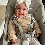 éléonore a rejoint le concours — aidez-le/la à gagner de superbes lots ! baby, child, smile, headband, bow, high_chair, sweater, clothing, seatbelt, indoor, person, cute, happy, infant, face, hand, pants, furniture, bright, portrait