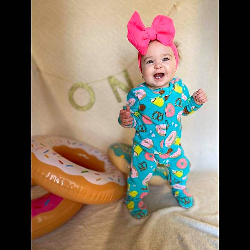 Haizley Steinhilber is registered to the contest to win money with this photo: baby, baby_products, baby_toddler_clothing, child, costume, hair_accessory, headgear, pajamas, person, pink, play, product, smile, toddler, toy, turquoise