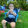 child, toddler, outdoor, grass, trees, cupcake, food, chair, blue_chair, picnic, play, summer, nature, barefoot, grass_field, smiling, people, kids, fun, daytime