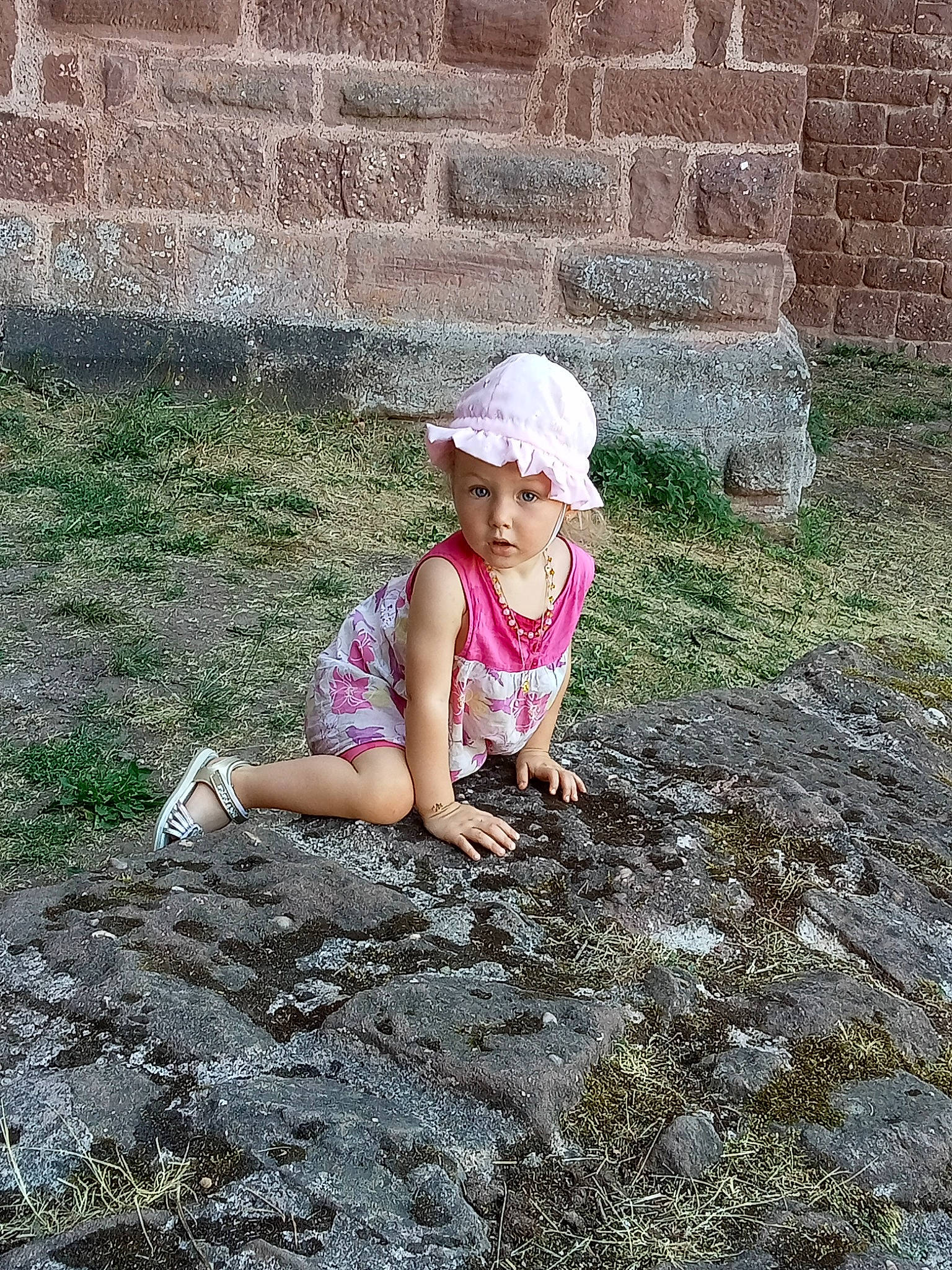 Lya participe au concours pour gagner de l'argent avec cette photo : asphalt, brick, brickwork, cap, child, cobblestone, crawling, flooring, fun, grass, hat, head, headwear, landscape, leisure, people_in_nature, person, road_surface, sitting, soil