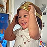 Louis is registered to the contest to win money with this photo: child, toddler, smiling, hat, viking_hat, indoor, person, baby, happy, playful, hand, clothing, furniture, television, toy, home, portrait, cute, fun, family