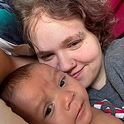 Leon is registered to the contest to win money with this photo: person, baby, face, smile, piercing, closeup, cuddling, portrait, skin, head, hair, expression, indoor, comfort, blanket, pillow, young_child, affection, casual, relaxation