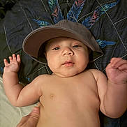 Leon joined the competition — help win amazing prizes! baby, bare_chest, bucket_hat, child, cute, feather_pattern, hand, hat, headwear, indoor, infant, lying_down, person, portrait, quilt, relaxed, skin, soft_lighting, supporting_hand, young_child