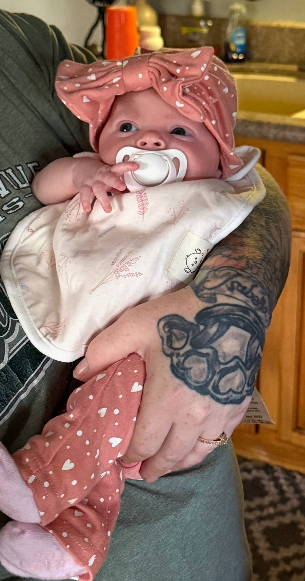Malina is registered to the contest to win money with this photo: arm, baby, bib, bow, closeup, clothing, cute, hand, headband, hearts, holding, indoor, infant, kitchen, pacifier, person, pink, skin, sleepwear, tattoo