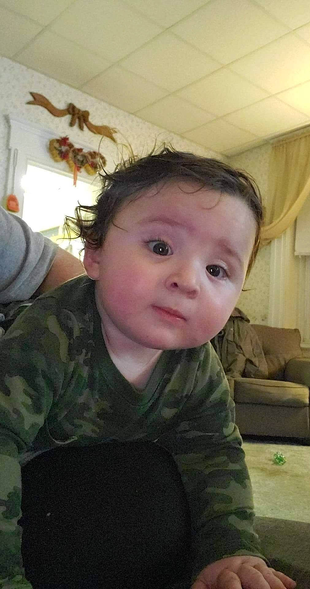 Karson is registered to the contest to win money with this photo: baby, baby_toddler_clothing, camouflage, cheek, cool, couch, curtain, eye, eyebrow, eyelash, forehead, human, interior_design, iris, jaw, living_room, military_camouflage, person, sofa_bed, studio_couch