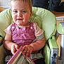 toddler, child, high_chair, book, reading, pink_clothing, blue_eyes, indoor, kitchen, baby, seatbelt, furniture, person, portrait, cute, holding, smiling, young_child, domestic, home