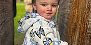 Alaric is registered to the contest to win money with this photo: background_people, bluey, child, clothing, cute, daylight, face, family, fleece_jacket, hand, nature, outdoor, park, person, portrait, smiling, toddler, tree, wood, young