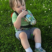 Alaric is registered to the contest to win money with this photo: bottle, cartoon, child, cute, daylight, dinosaur, fun, grass, green_shirt, grey_shorts, happy, nature, outdoor, playing, sitting, sneakers, summer, toddler, wet_hair, white_socks