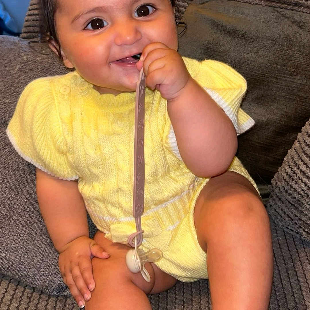 Amarah joined the competition — help win amazing prizes! baby, barefoot, child, couch, cute, face, foot, hand, happy, indoor, infant, pacifier, person, pigtails, plush, sitting, skin, smiling, textured_fabric, yellow_clothing