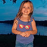 child, girl, smiling, portrait, outdoor, lakeside, lake, water, evening, sunset, sky, clouds, tree, landscape, standing, shorts, shirt, sunglasses_design, long_hair, nature